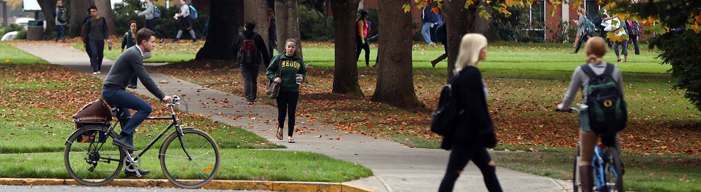 Student walking and biking through campus Student walking and biking through campus