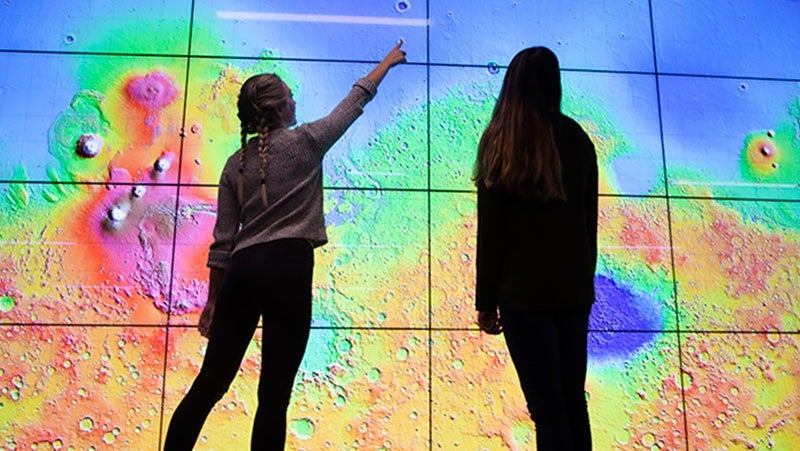 Two students working at a giant screen in the visualization lab