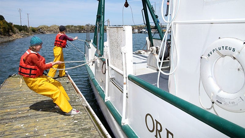 Two students pulling the Oregon Institute of Marine Biology boat into the dock 