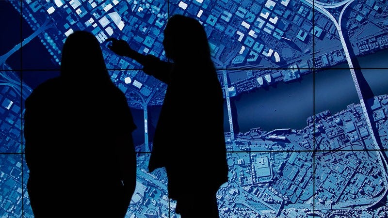 Two students pointing at a giant map display in the visualization lab 