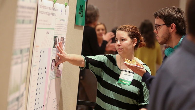 A student presenting her research poster at the Undergraduate Research Symposium