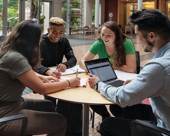 diverse group of two men and two women studying at tabletop in Lillis Hall