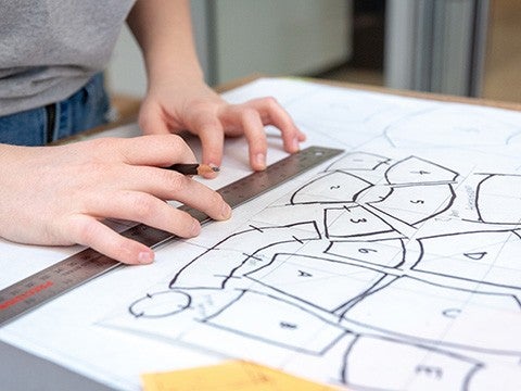 Hands adjusting a ruler above a page with a product design