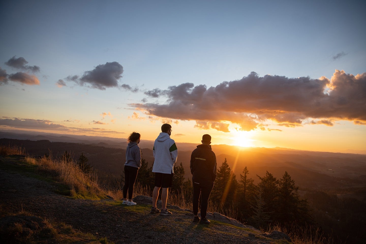 Trio of students watching the sunrise atop Spencer Butte in Eugene, Oregon.