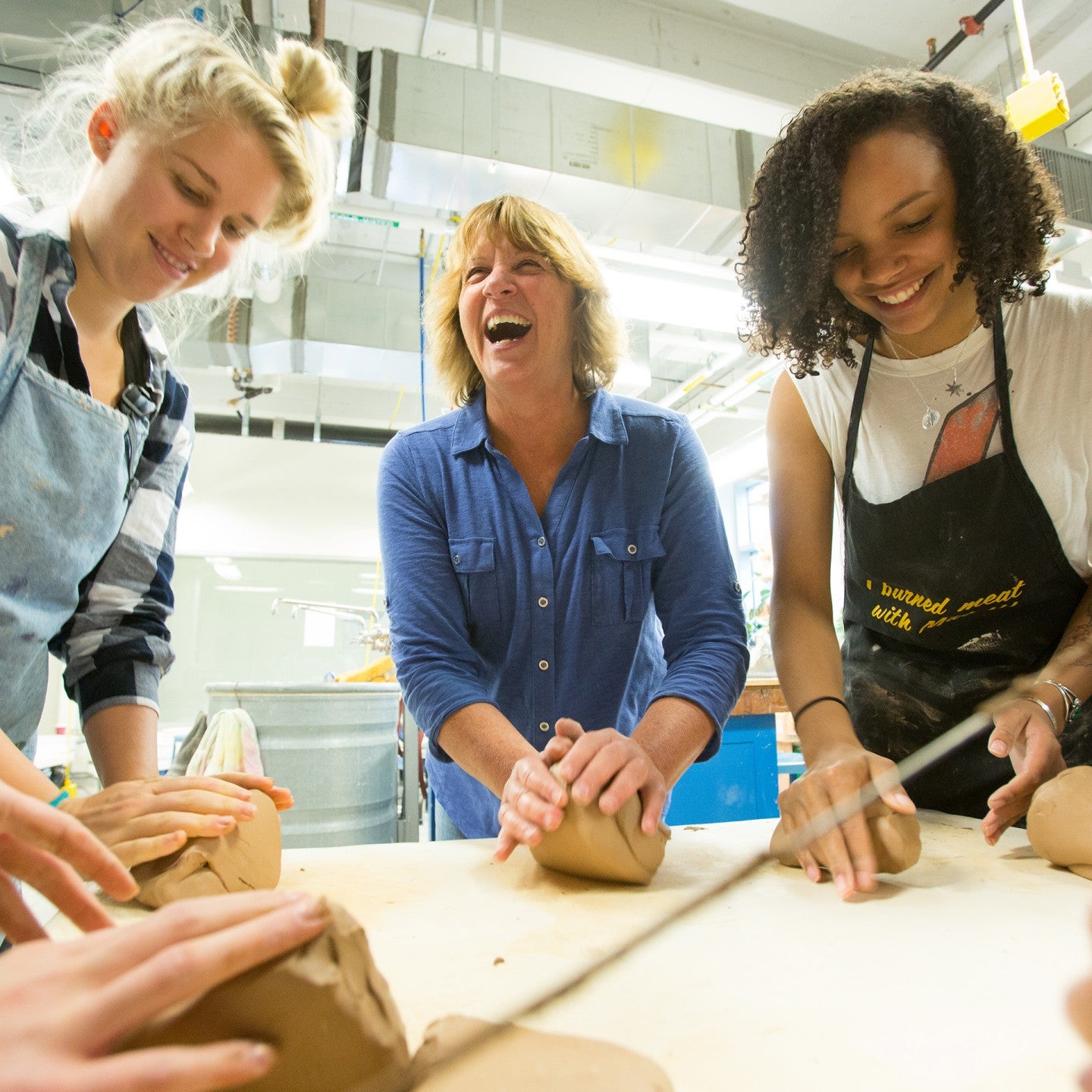 Group of women laughing, throwing clay in the ceramics studio.