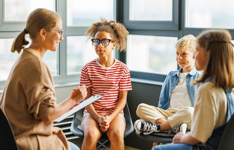 Woman surveying group of three elementary-aged students.