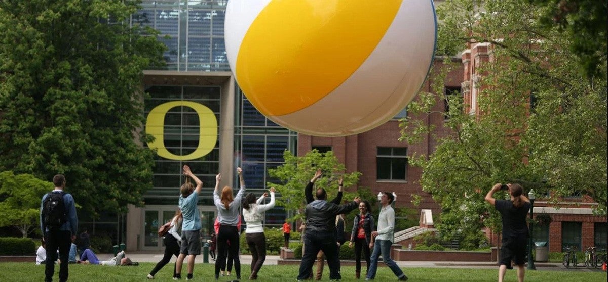 Group of students playing with enormous beach ball on the University of Oregon quad.