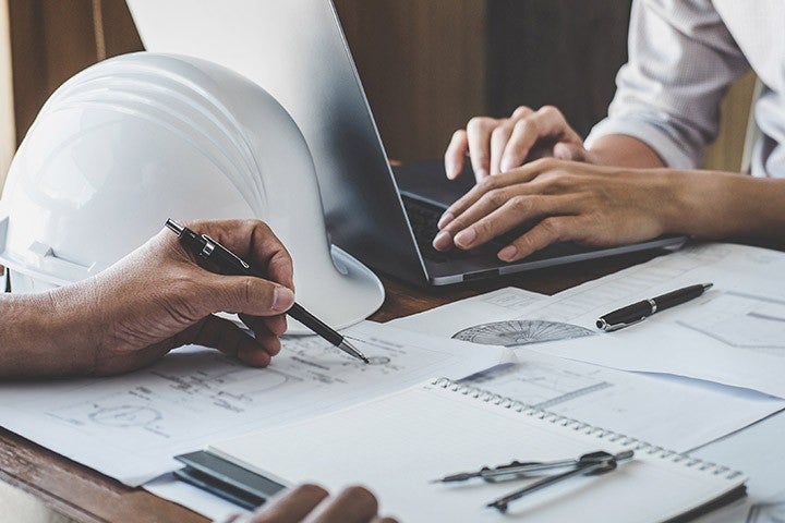 Two people working with drafting tools and construction plans