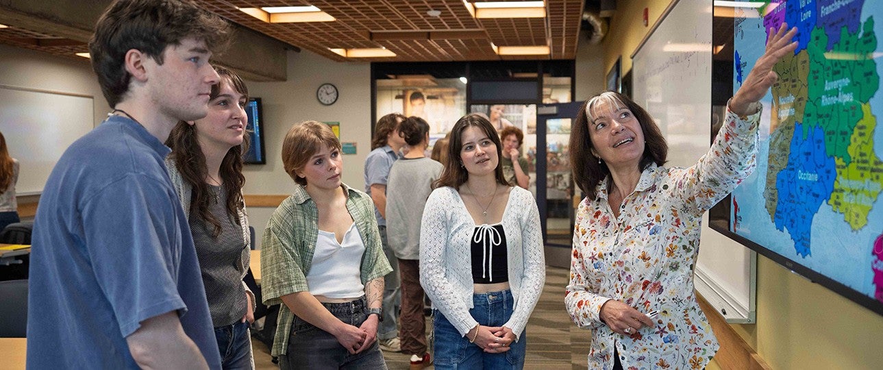 A french teacher pointing to a map in front of students