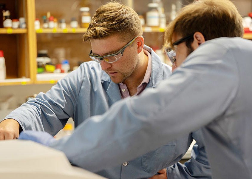 Carl Brozek and a graduate student review how to use a spectrophotometer