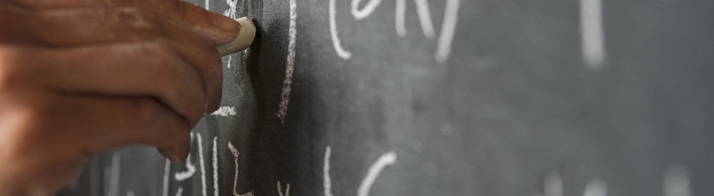 Hand writing mathematical equations on a chalkboard