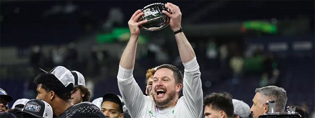 Dan Lanning holds up a Big Ten football championship trophy