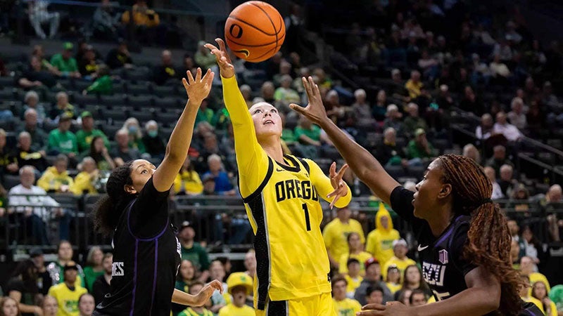 three basketball players reach for the ball