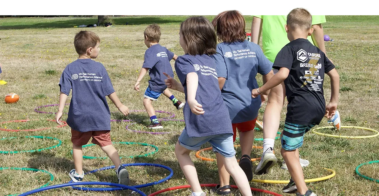 children running over hula hoops in a grassy area during a camp