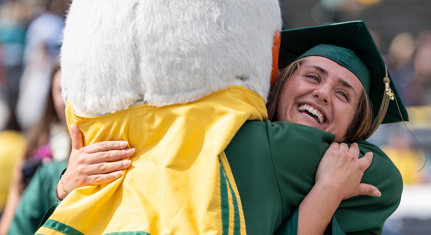 a graduating student hugs the Duck at commencement