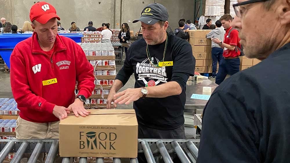 Vice President and General Counsel Kevin Reed and Faculty Athletics Representative Tim Gleason sealing food boxes for distribution