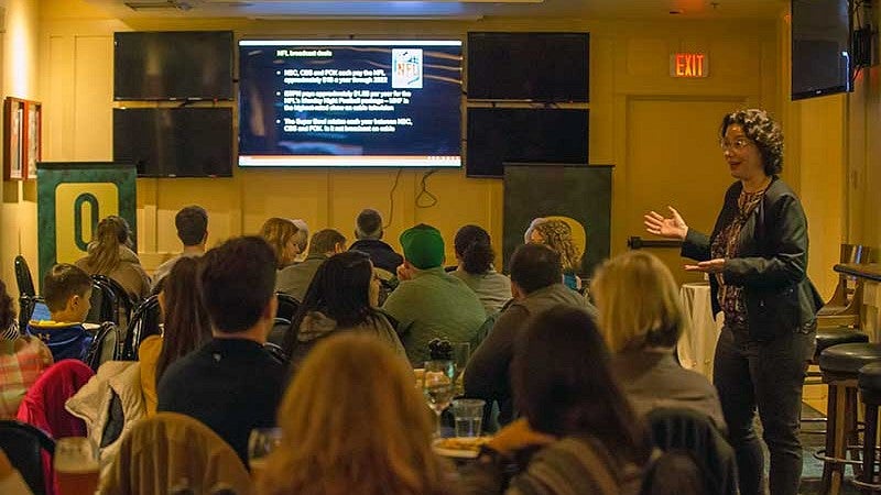 Whitney Wagoner, director of the UO’s Warsaw Sports Marketing Center, delivering a pub talk on Super Bowl unveiled: Behind the business of the big game