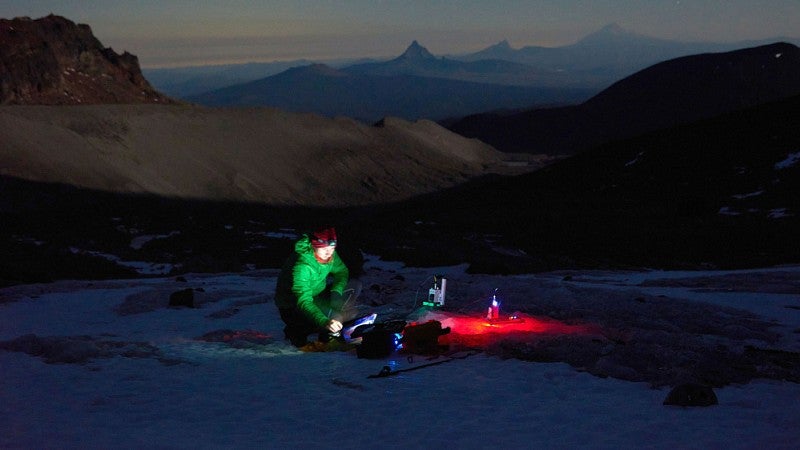 researcher in the snow using a portable laser that can measure the composition of glacial ice