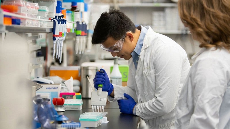 Knight Campus lab worker filling testing equipment with a pipette