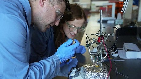 Male and female student in lab coats working on an aperatus