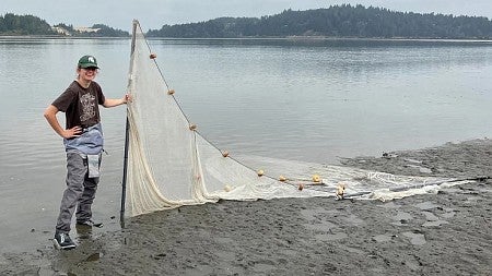 Hope Healey holding a seine net on the beach