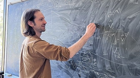 Jesse Hall writing an equation on a chalkboard