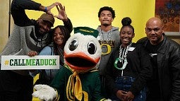 Family posing with the Duck and a Call Me a Duck sign at the admissions event for the Rose Bowl