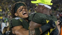 Two Oregon players smiling and hugging after winning the game