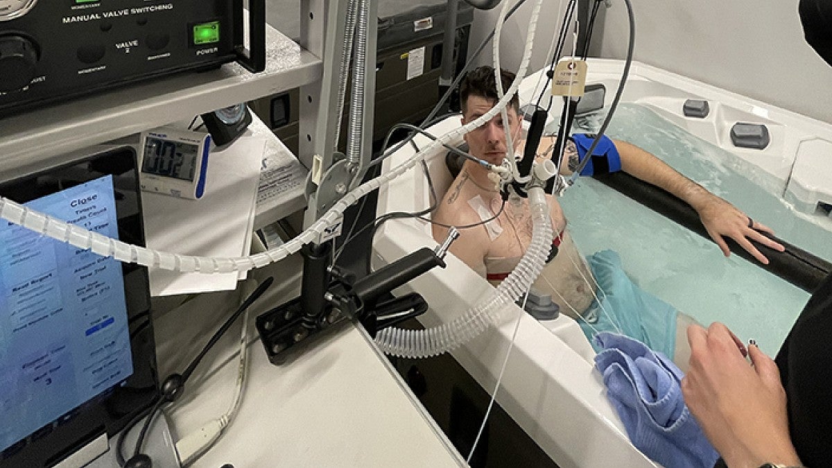 An athlete soaks in a hot tub while hooked up to lab equipment