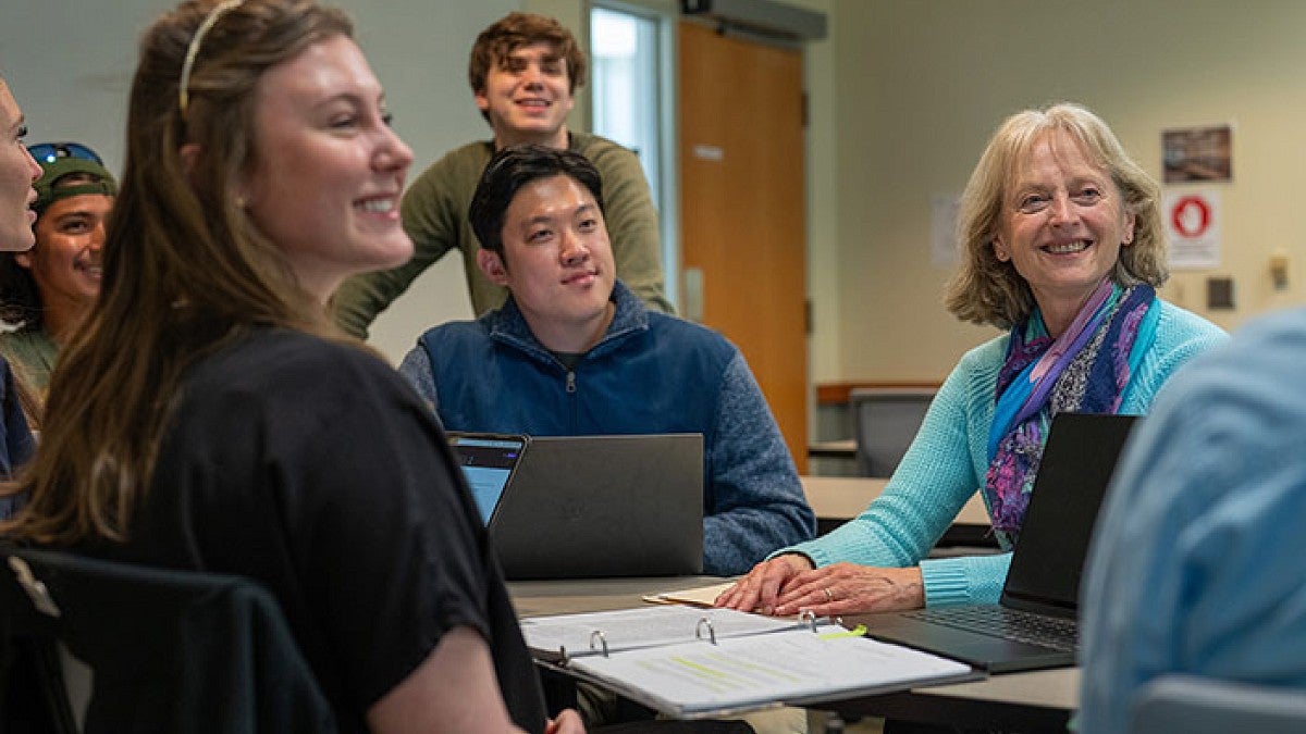 An instructor with a group of students sitting at a table smiling