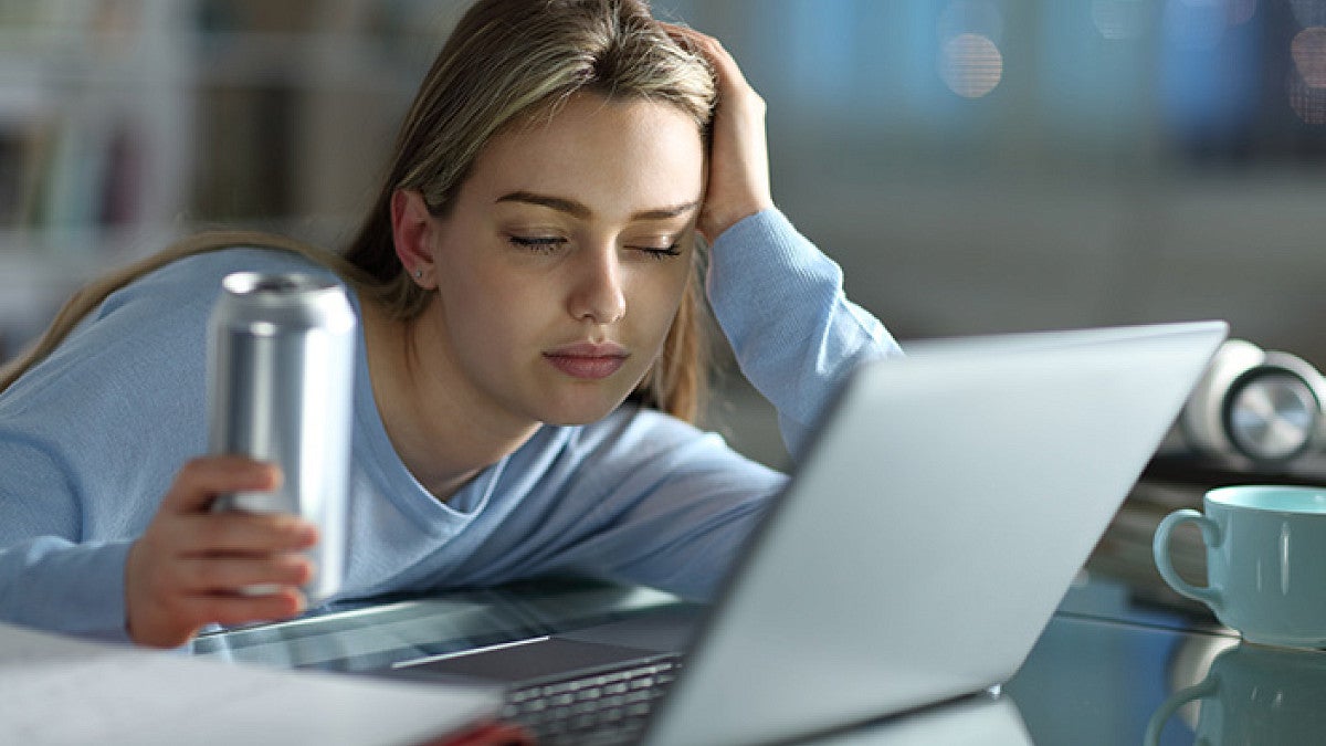a person looks sleepy while working on a laptop