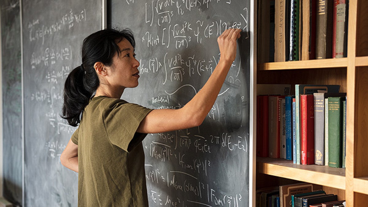 Particle physicist Tien-Tien Yu draws equations on a blackboard