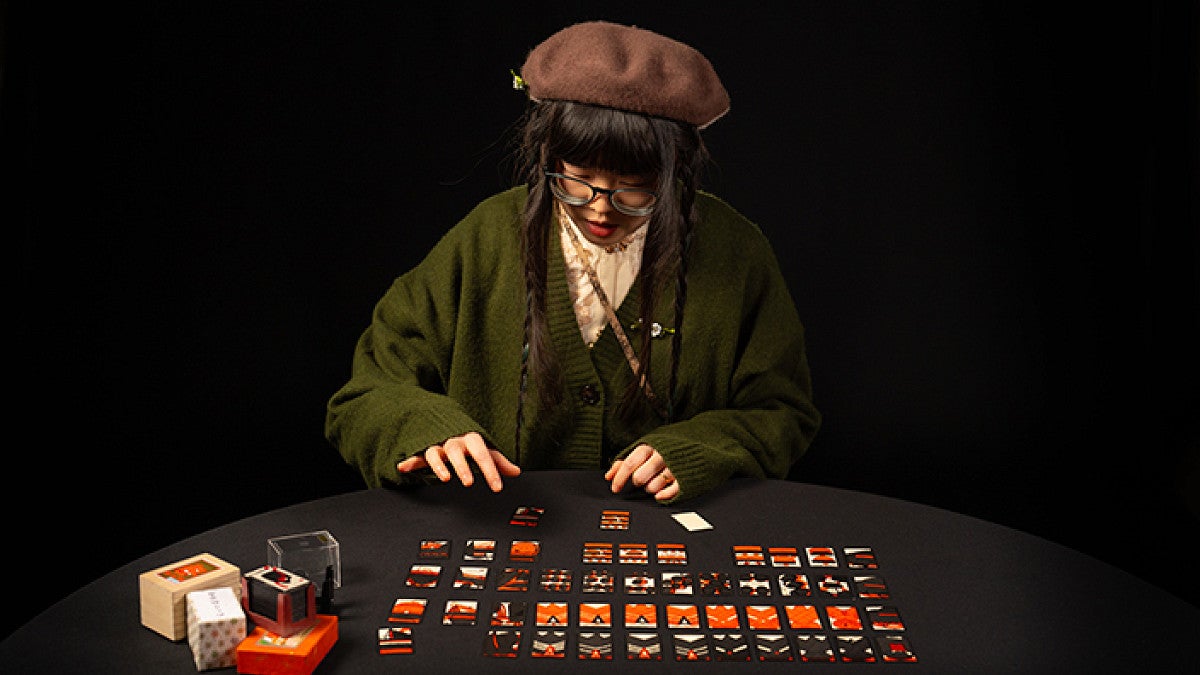 Mew Jiang sitting at table with karuta cards