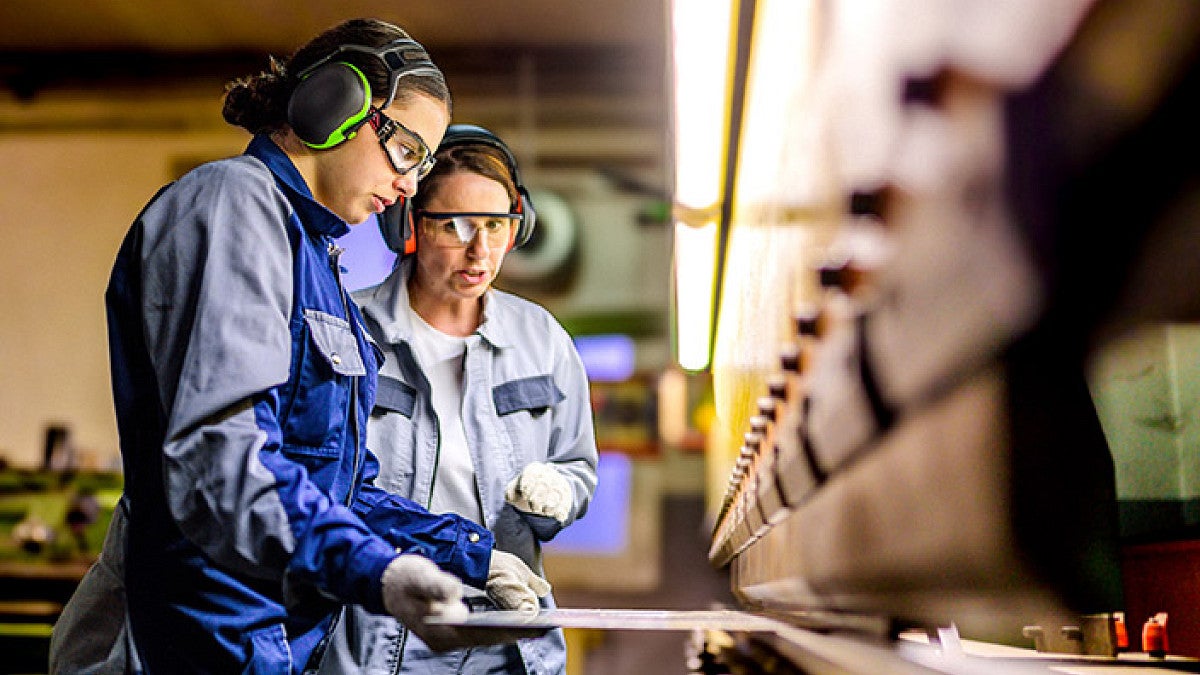 two people in protective gear working with machinery