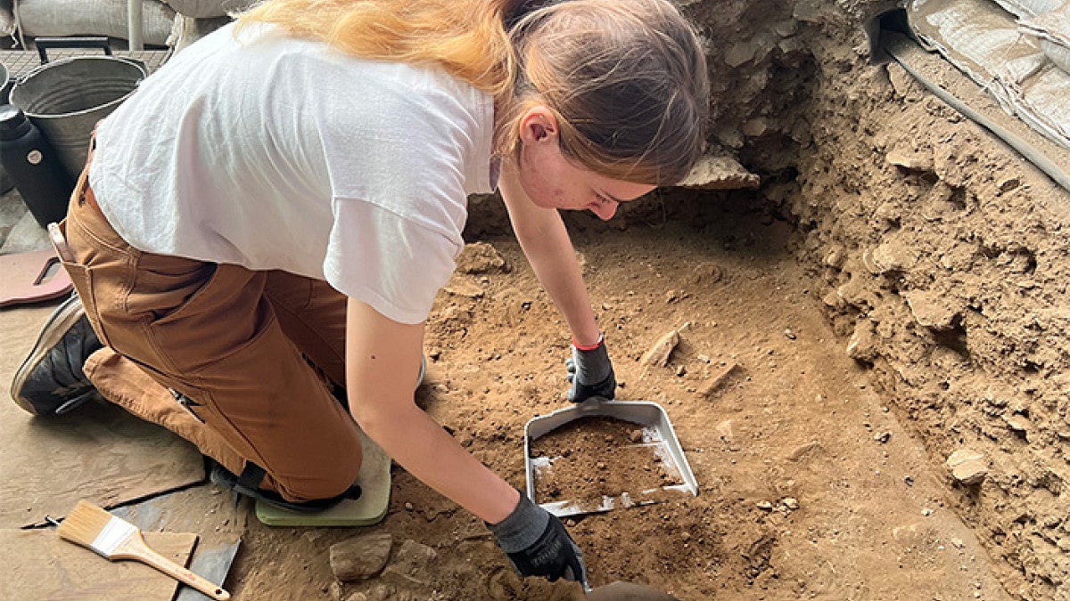 a student sifts through the dirt at an archeological site