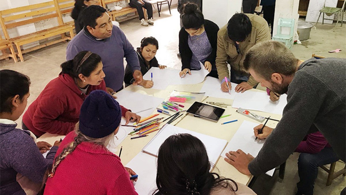 people drawing on paper while gathered around a table