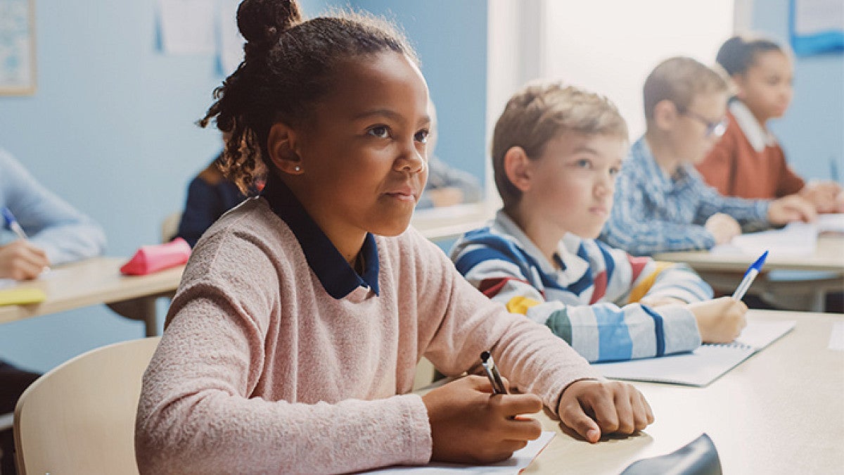 children sitting at desks ready to write on paper