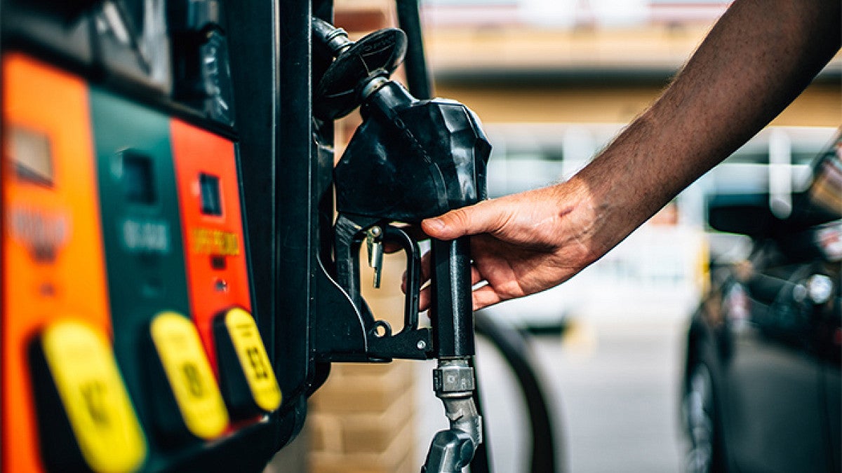 a person reaches for a gas pump nozzle
