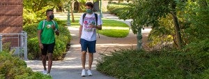 Two students walking through campus wearing face masks