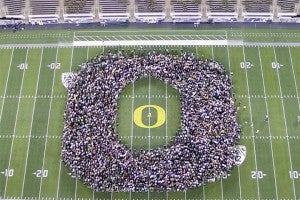 Class of 2025 standing on Autzen Stadium's field in the shape of an "O"