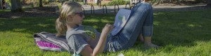 Photographic image depicts a student lying down in grass on the University of Oregon campus, highlighting passages in a text document. Photographic image depicts a student lying down in grass on the University of Oregon campus, highlighting passages in a text document.