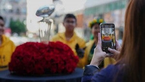 Fan taking a photo with the Rose Bowl trophy